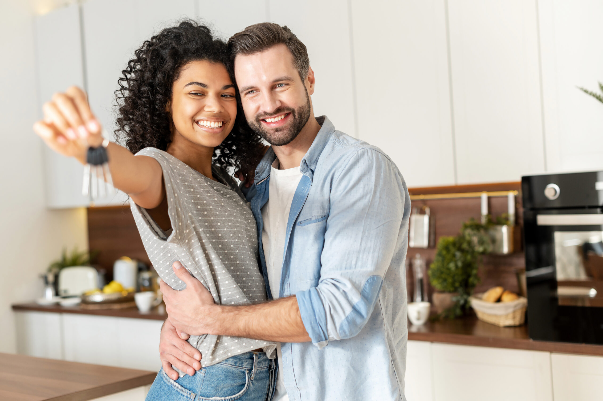 Young,Interracial,Married,Couple,Homeowners,Smiling,,Showing,Keys,From,A